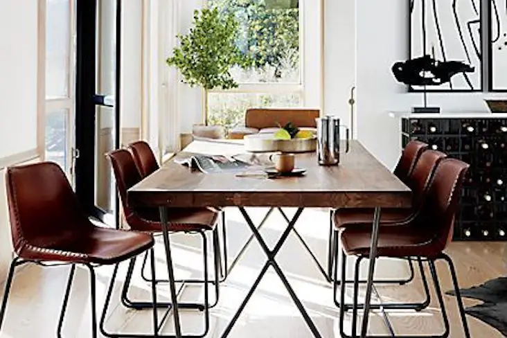 exemple salle a manger style masculin table épurée bois et métal piètement oblique chaises vintage en cuir ambiance lumineuse