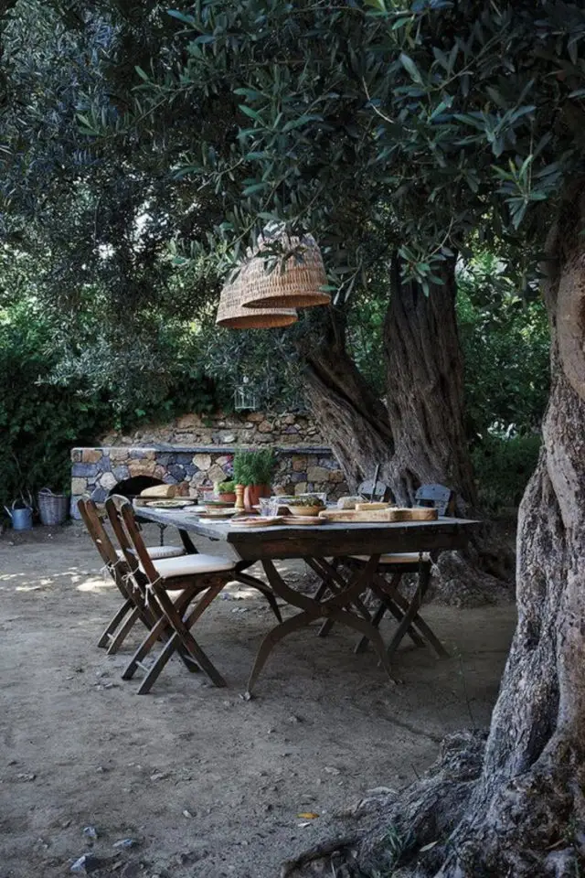 repas en exterieur grande table familiale sous les arbres luminaire tressés
