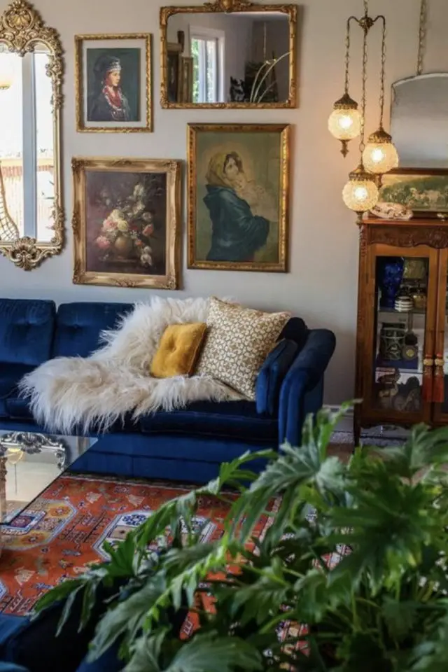 exemple salon eclectique canape couleur bleu velours capitonné plaid en fourrure blanche cadres et peintures anciens