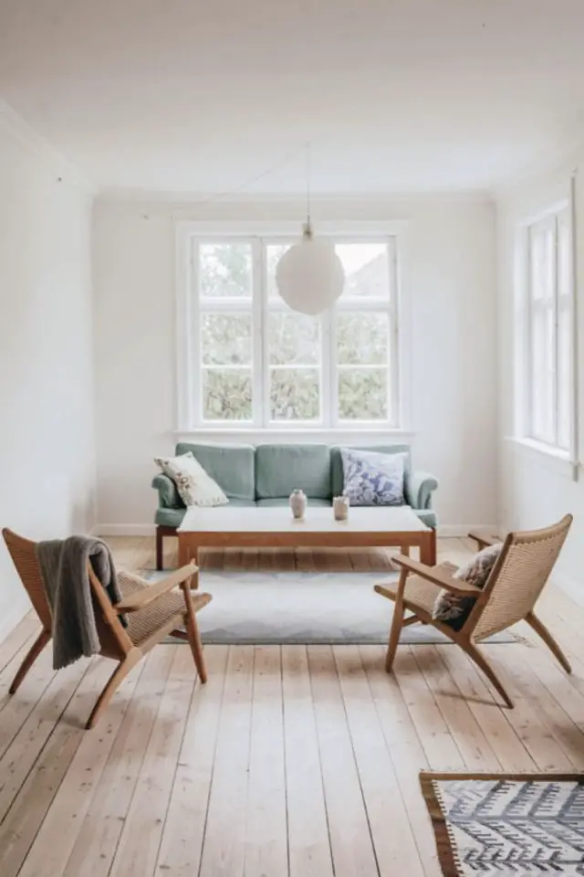 salon style minimal luminaire scandinave suspension blanche milieu plafond petite pièce à vivre canapé vert fauteuil cannage