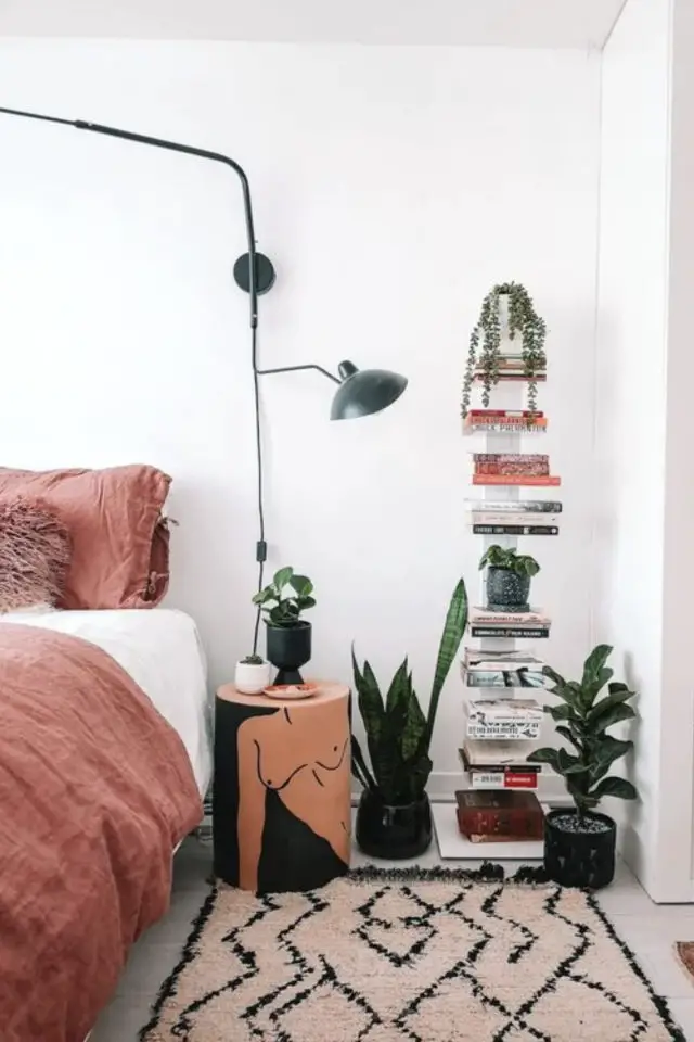 deco eclectique petite chambre adulte pile de livres à côté du lit parure blanche et roses petites plantes vertes