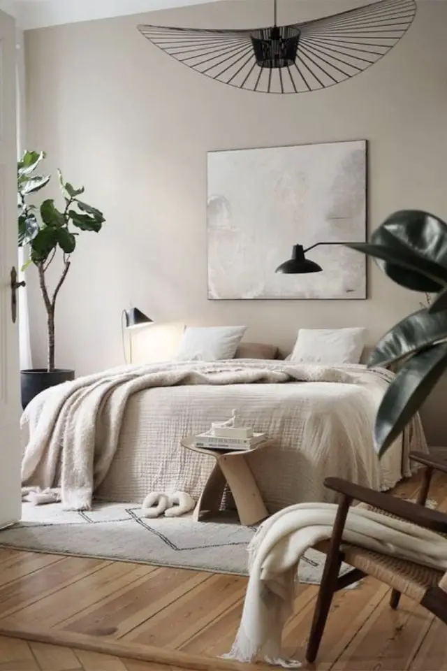 decoration chambre adulte minimale et chaleureuse parure de lit couleur beige naturel neutre petit bout de canapé tabouret lampe noire tableau abstrait dessus du lit
