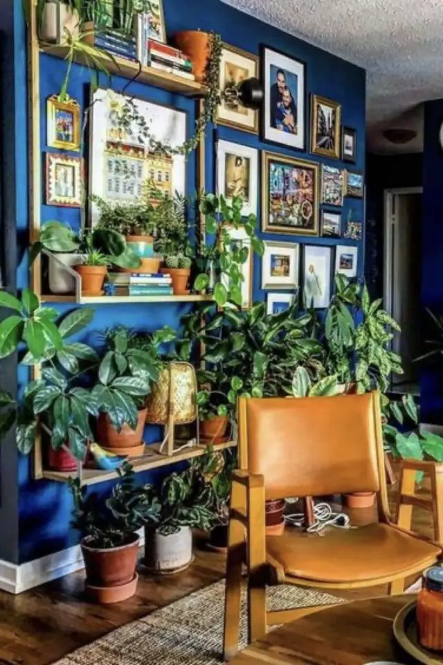 exemple deco salon eclectique couleur mur bleu pétrole plantes vertes étagères murale cadres poster fauteuil bois et cuir vintage