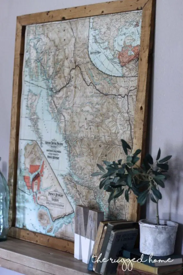 decor mural carte geographie vintage encadrée et posée sur un meuble petite plante verte objets décoratifs