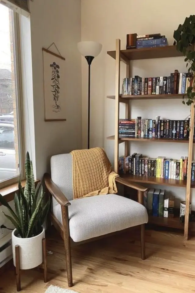 meubler angle salon fauteuil cosy vintage en bois noyer et tissu gris clair plaid jaune étagère bibliothèque coin lecture plante près d'une fenêtre