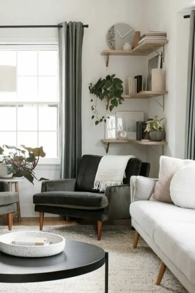 meubler angle salon fauteuil cosy en velours vert gris chic élégant étagères murales d'angle en bois accessoires déco plaid canapé fenêtre