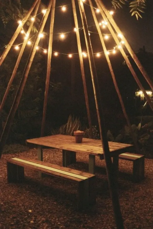 eclairage jardin exemple a copier création d'un tipi en bois avec guirlande lumineuse au dessus table de pique-nique