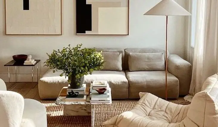 interieur minimal et chaleureux exemple salon séjour canapé fauteuil couleur neutre tableaux abstrait luminaire tapis simplicité épuré