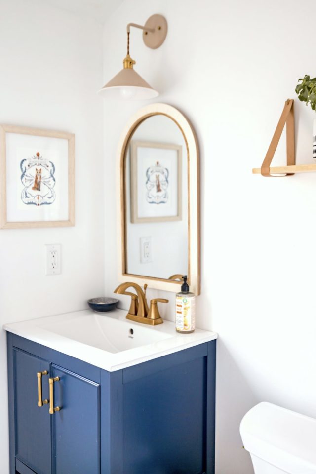 salle de bain cosy et chaleureuse meuble de salle de bain bleu miroir arrondi sur le haut déco murale et applique luminaire