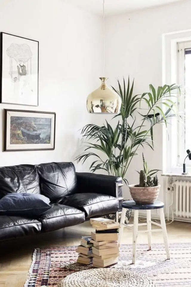 decor salon canape noir cuir élégant forme vintage mur blanc contraste plante verte déco mur petit tabouret