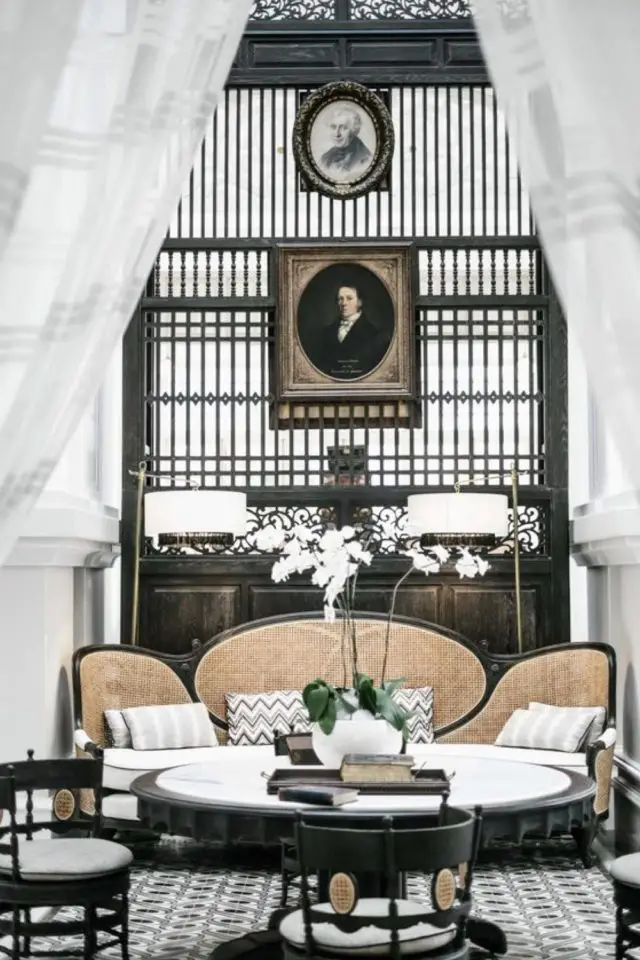 style decoration coloniale exemple salon séjour appoint banquette en cannage portrait ancien encadré claustra intérieur en bois table ronde en marbre blanc carreaux de ciment luxe chic