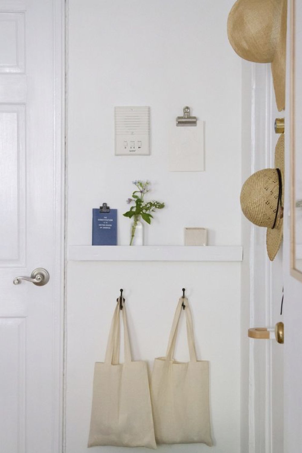 decoration petite entree accueillante moderne peinture blanche lumineuse appartement étagère patère tote bag chapeau minimalisme