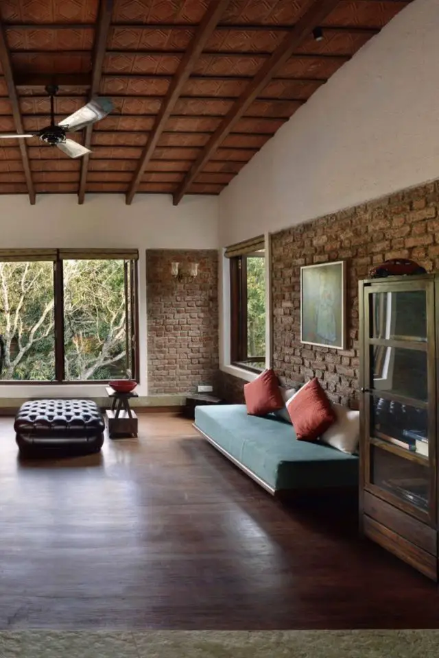 visite maison grand espace ouvert materiaux bruts salon épuré meuble essentiel mur en brique rouge et ciment