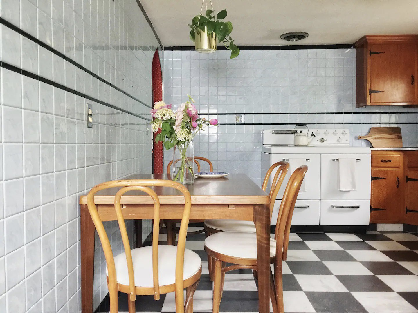 visite deco appartement mid century modern chaise vintage coin repas cuisine sol noir et blanc cuisinière carrelage mur bleu pastel et frise noire