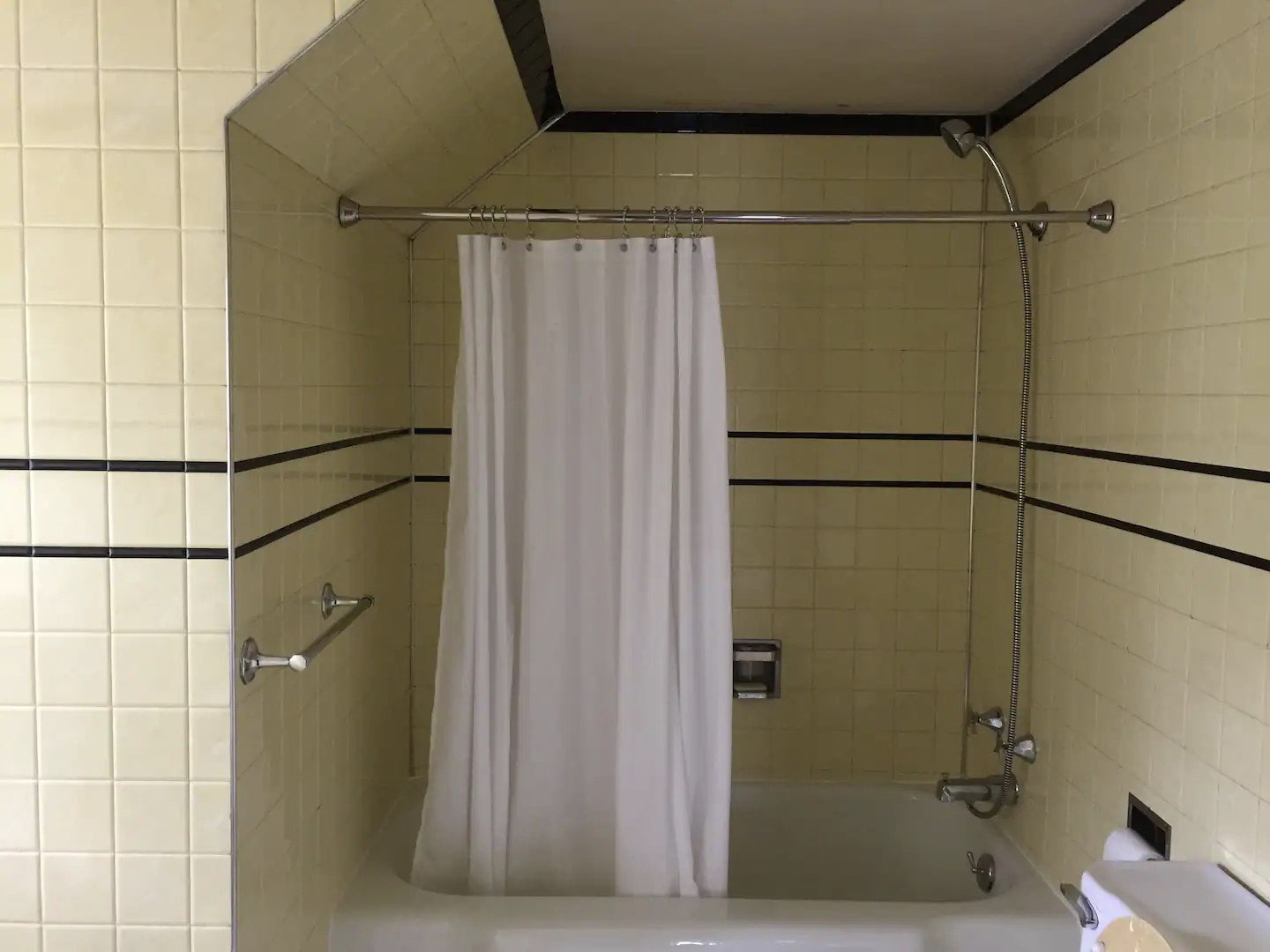 visite deco appartement mid century modern salle de bain baignoire robinetterie chromée rideau de douche simple blanc carrelage jaune pastel