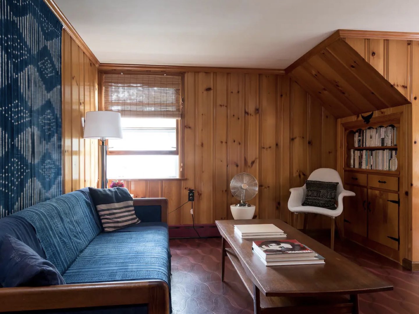 visite deco appartement mid century modern salon séjour revêtement mural bois lambris vernis couleur complémentaire bleu textile canapé et tenture mur