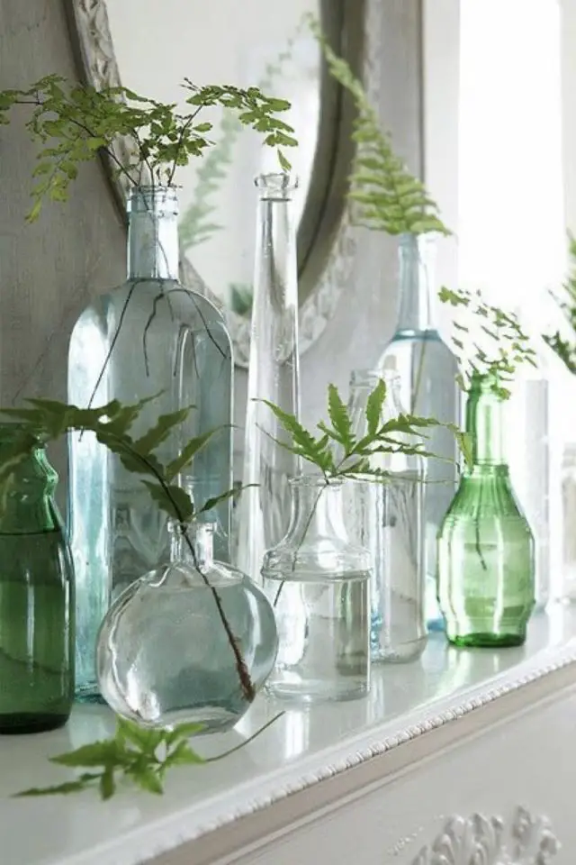 deco interieur materiau verre exemple assemblage de vases transparents et coloré fleurs plante déco dessus cheminée