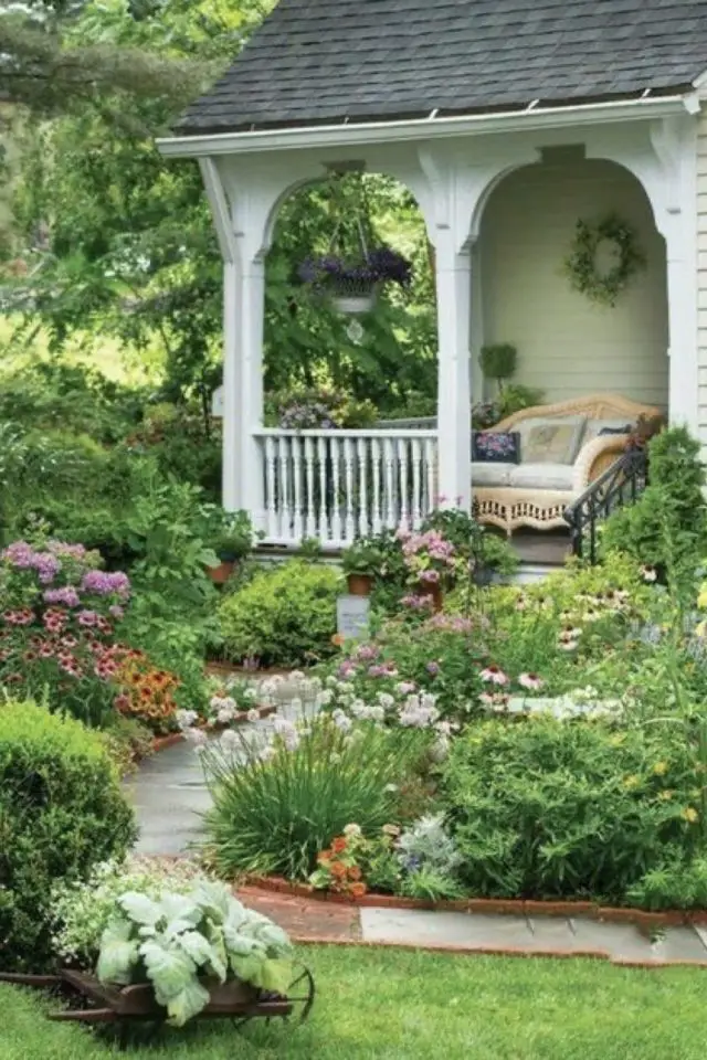 decor jardin devant maison exemple allée dalle de béton massifs de fleurs colorées porche fauteuil canapé accueillant 