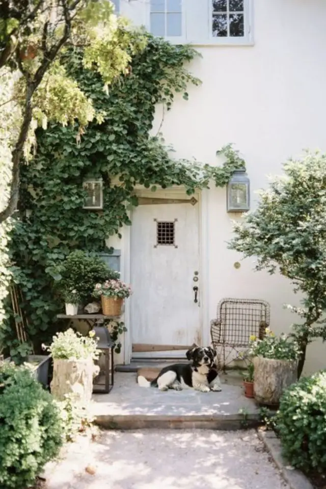 decor jardin devant maison exemple allée en pierre petit fauteuil à côté de la porte d'entrée arbre pot de fleur posé petite table