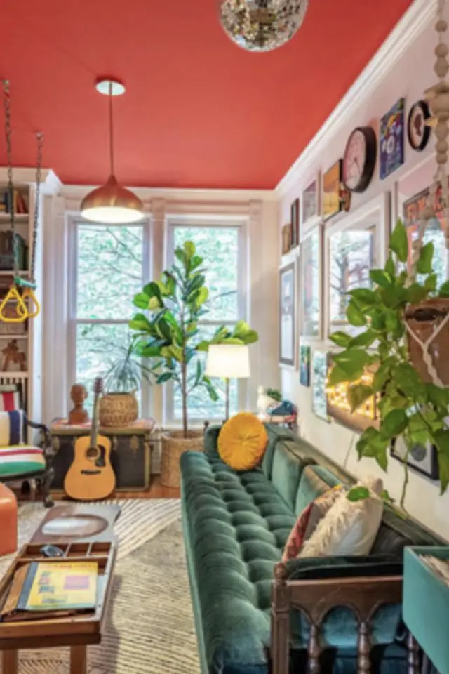 visite deco maison decor eclectique plafond peint en rouge salon séjour canapé en velours vert plantes figuier guitare galerie de cadres