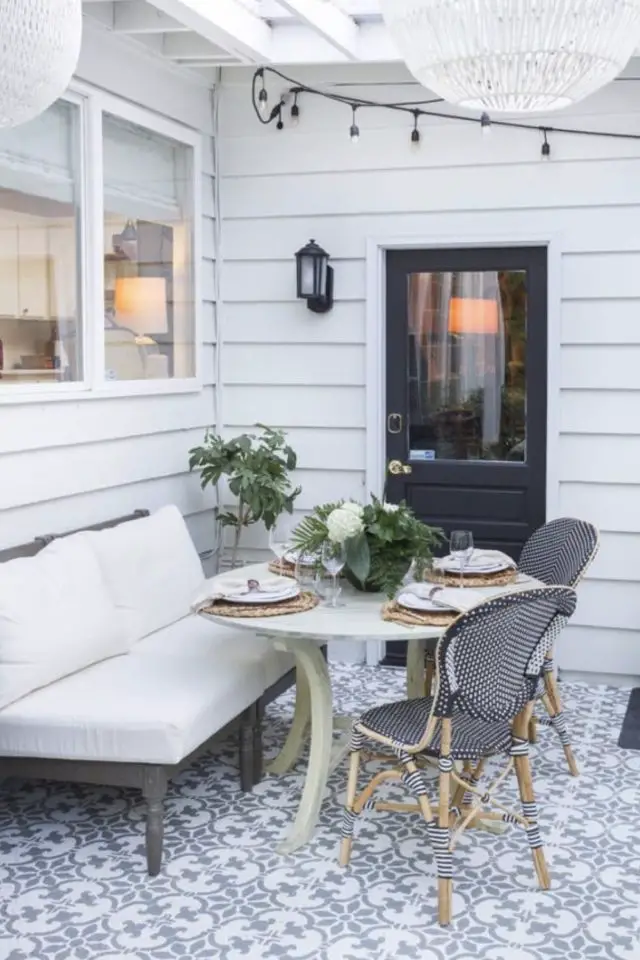 amenagement deco petit patio exterieur lambris outdoor façade blanche carrelage motif banquette table repas avec chaise bistrot charmant et lumineux applique murale à côté de la porte d'entrée