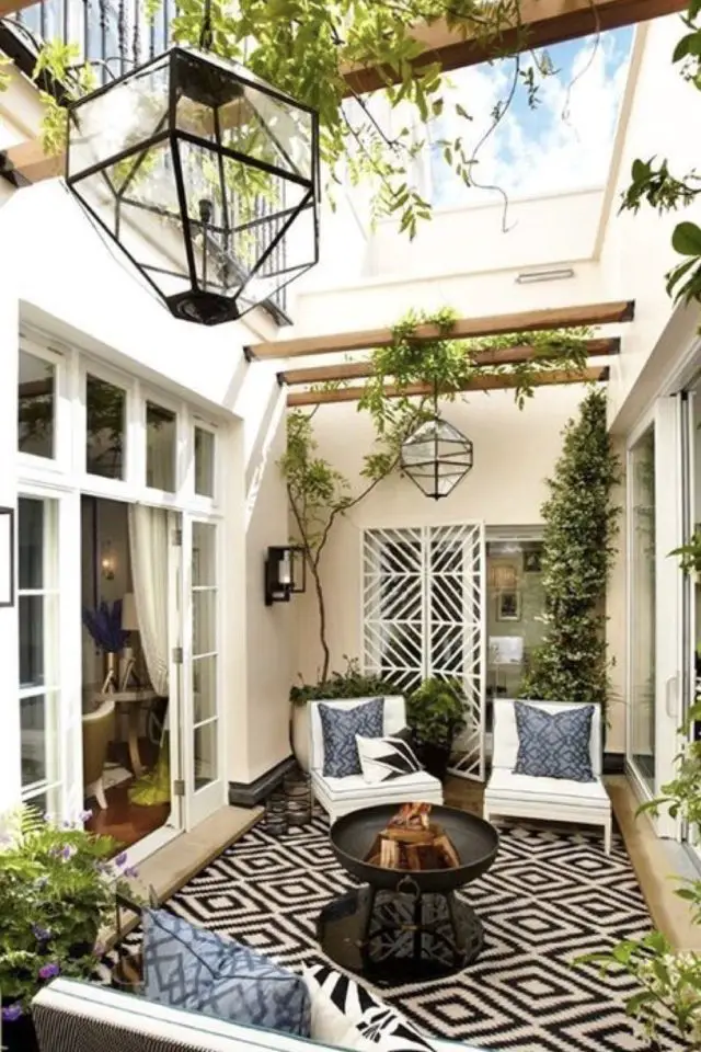 amenagement deco petit patio exterieur suspension extérieure poutre entre deux façades fauteuils de jardin blancs petite table basse tapis noir et blanc plante grimpantes
