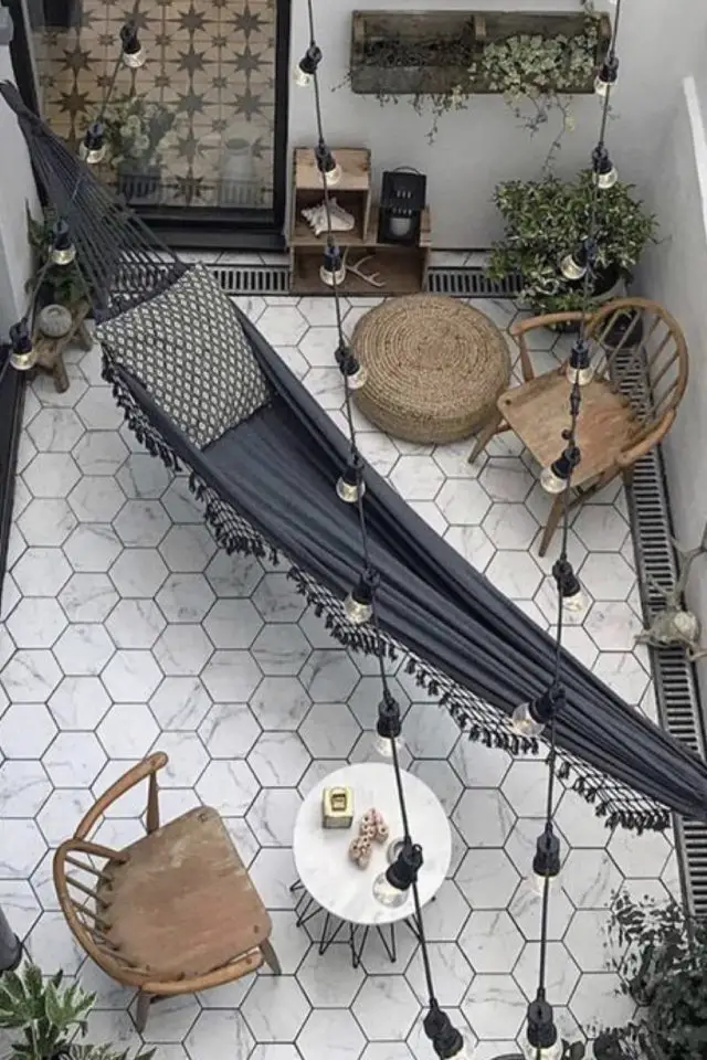 amenagement deco petit patio exterieur sol blanc forme hexagonal moderne bohème chic hamac gris fauteuil en bois petit coin repas dehors maison de ville