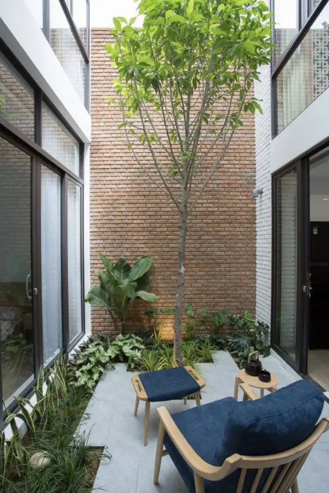 amenagement deco petit patio exterieur moderne mur en brique authentique couple ou personne seule fauteuil confortable décaissement végétal jardinière terrasse en béton