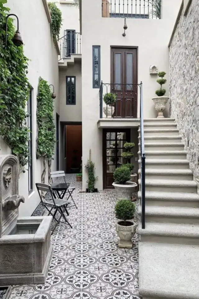 amenagement deco petit patio exterieur charmant élégant classique avec escalier maison de ville petit espace carrelage terrasse pratique avec motif fontaine contre façade pot de fleurs avec arbustes mur végétal petite table et chaise pliante pour prendre un café