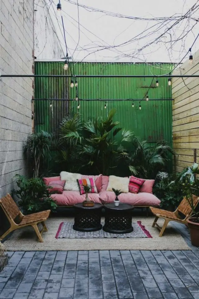 deco patio terrasse convivial mur caché par tôle ondulée verte mur en bois revêtement façade tapis coin détente canapé fauteuil jardinière plante verte