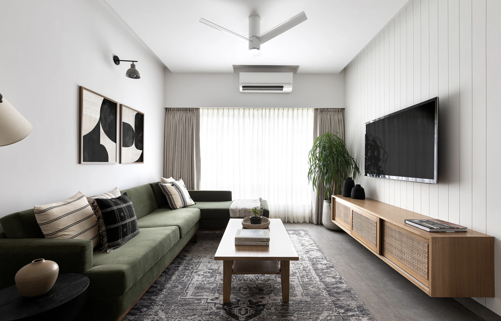 idee decoration appartement moderne et slow living salon séjour grand canapé vert meuble TV en cannage table basse rectangulaire en bois tapis gris grande baie vitrée avec voilage