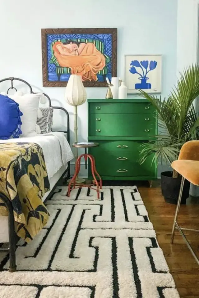 interieur vintage caracteristique decor chambre à coucher commode vert franc tapis noir et blanc tête de lit en métal tabouret industriel plante verte touche de bleu électrique
