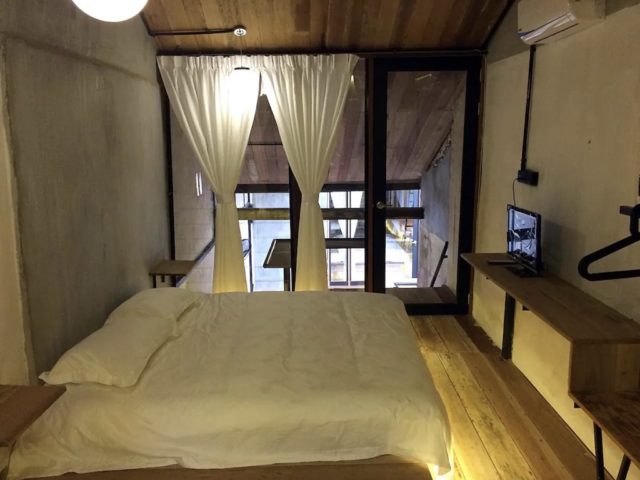 logement vacances traditionnel malaisie melaca chambre double adulte grand lit mur en béton voilage blanc chic et élégant