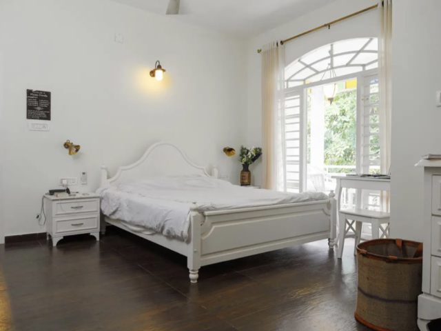 villa familiale ferme kerala nature chambre parentale blanche simple baie vitrée avec imposte cintrée parquet bois sombre contraste