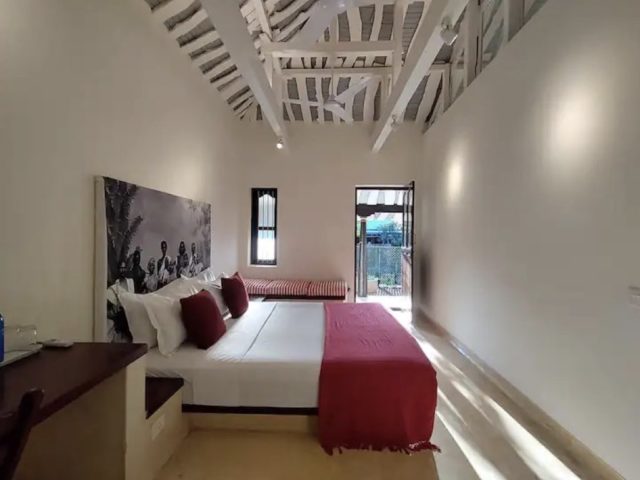 villa traditionnelle tamil nadu architecture chambre avec poutre apparente blanche tête de lit porte donnant sur le jardin