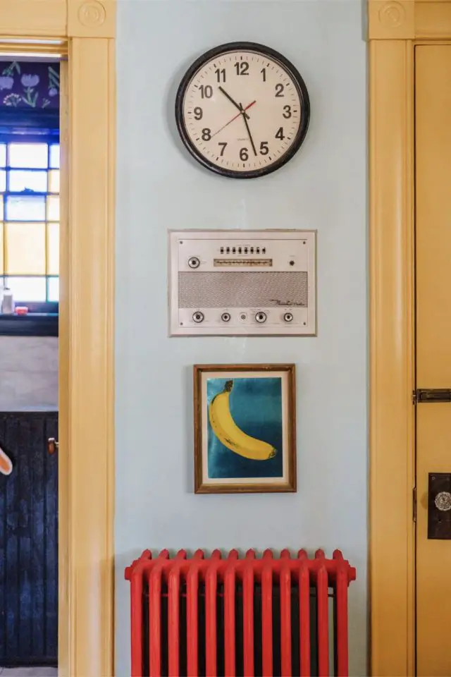 visite deco maison hyper coloree et joyeuse décoration murale horloge vintage papier peint banane encadré radiateur en fonte peint en rouge