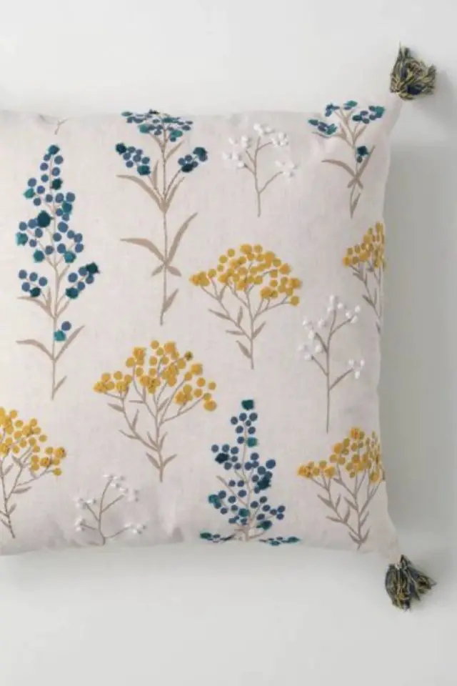 broderie florale exemple decoration détail coussin fond blanc petite fleur brodée bleu et jaune