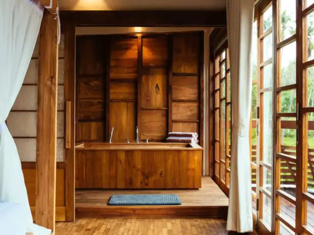 bungalow haut de gamme voyage indonesie salle de bain avec baignoire habillage en bois cloison original cosy vue sur la nature baie vitrée