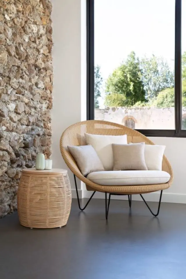 decor interieur moderne chaleureux cannage tendance rotin salon séjour mur en pierre petit fauteuil pied en métal noir coussin