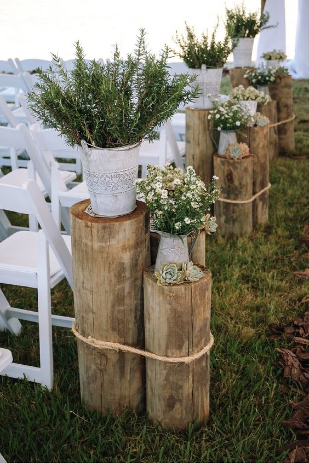 decoration mariage champetre romantique détail décoratif à côté des chaises cérémonie tronc d'arbres pots de fleur plantes ficelle