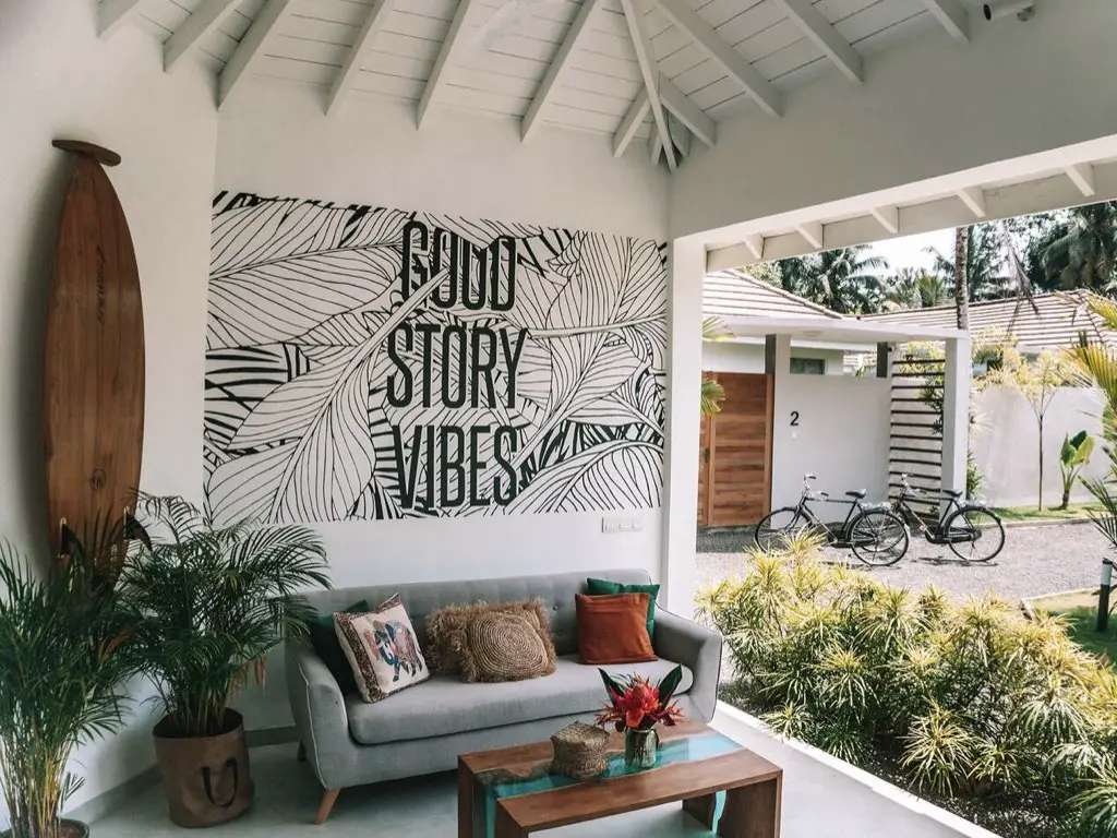 jolie maison vacances luxe sri lanka espace salon entre intérieur et extérieur déco murale positive planche de surf en bois canapé gris