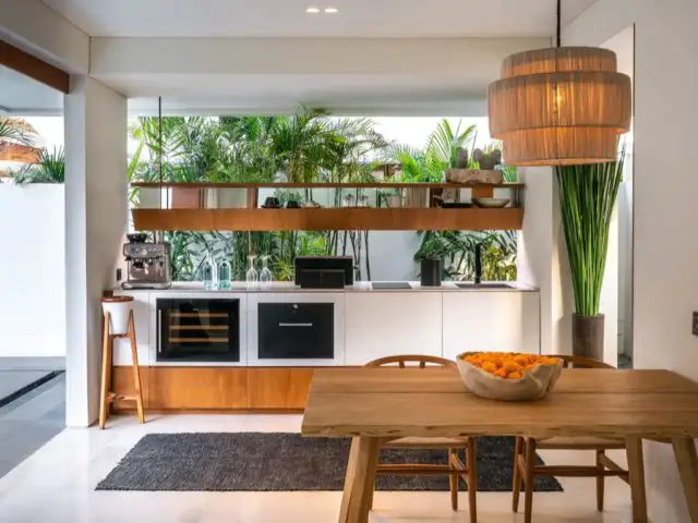 villa haut de gamme voyage bali cuisine en linéaire blanche ouverte salon salle à manger bois vue sur l'extérieur