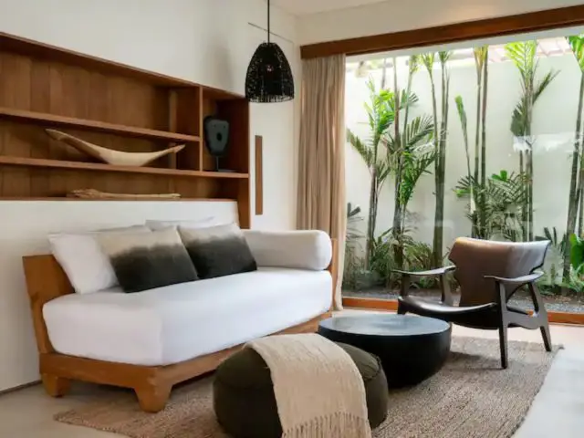 villa haut de gamme voyage bali espace salon avec grande baie vitrée plantes trocipale meuble en bois niche rangement canapé cosy design