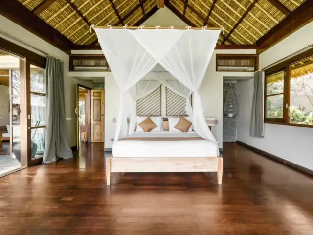 voyage indonesie bali hebergement luxe suite parentale lit à baldaquin parquet sombre contraste voilage blanc