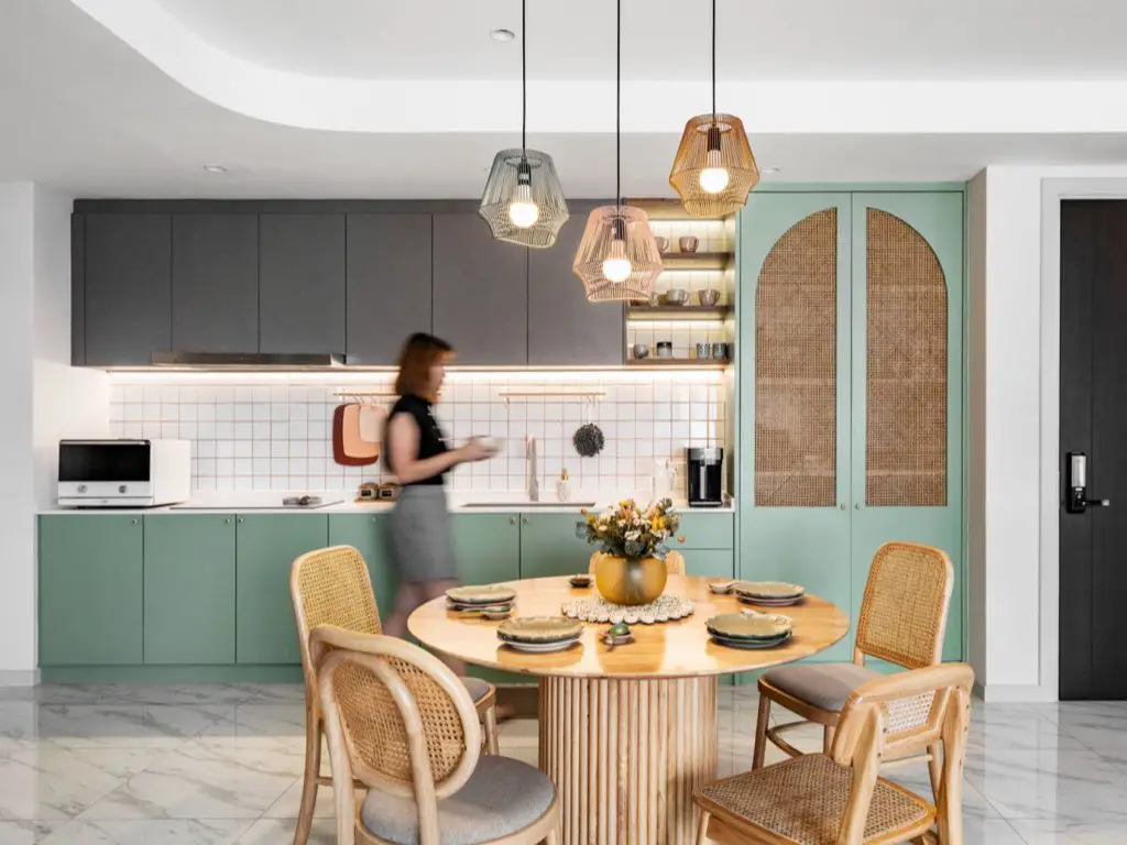 appartement moderne chic colore cuisine ouvert en linéaire avec coin repas table ronde meubele vert céladon et gris porte en cannage tendance