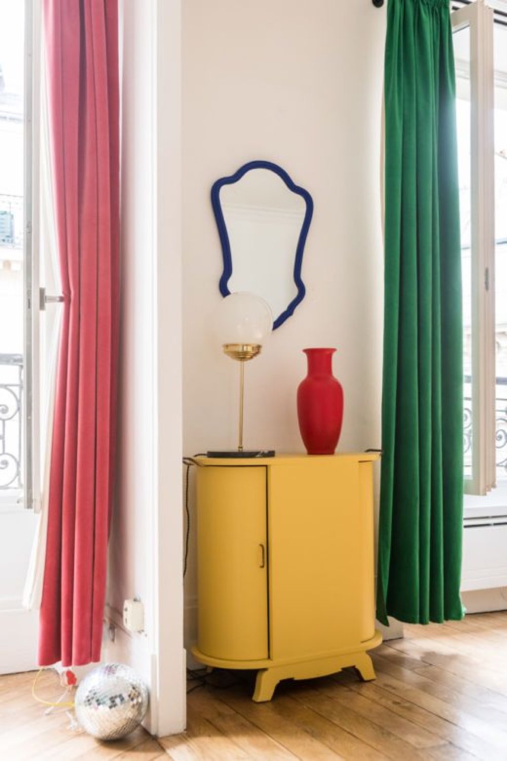 deco touche couleur relooking meuble petit cabinet jaune vintage angle arrondi pan de mur blanc rideaux colorés miroir noir appartement parisien