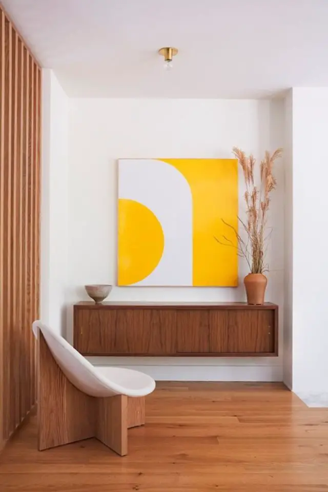 decor vintage moderne exemple entrée recoin petit espace claustra bois meuble mural sombre fauteuil courbe tableau jaune et blanc