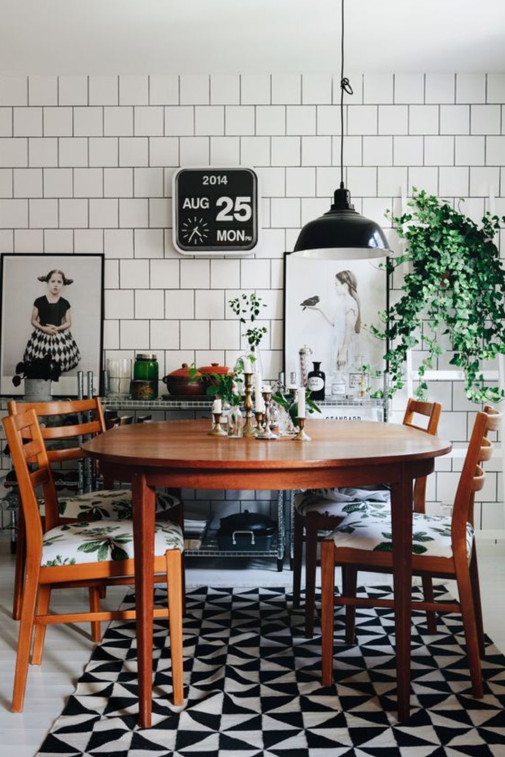 exemple decor salle a manger reussi ambiance vintage table en bois ronde tapis noir et blanc revêtement mural carrelage blanc objet déco rétro petite plante verte suspension noir