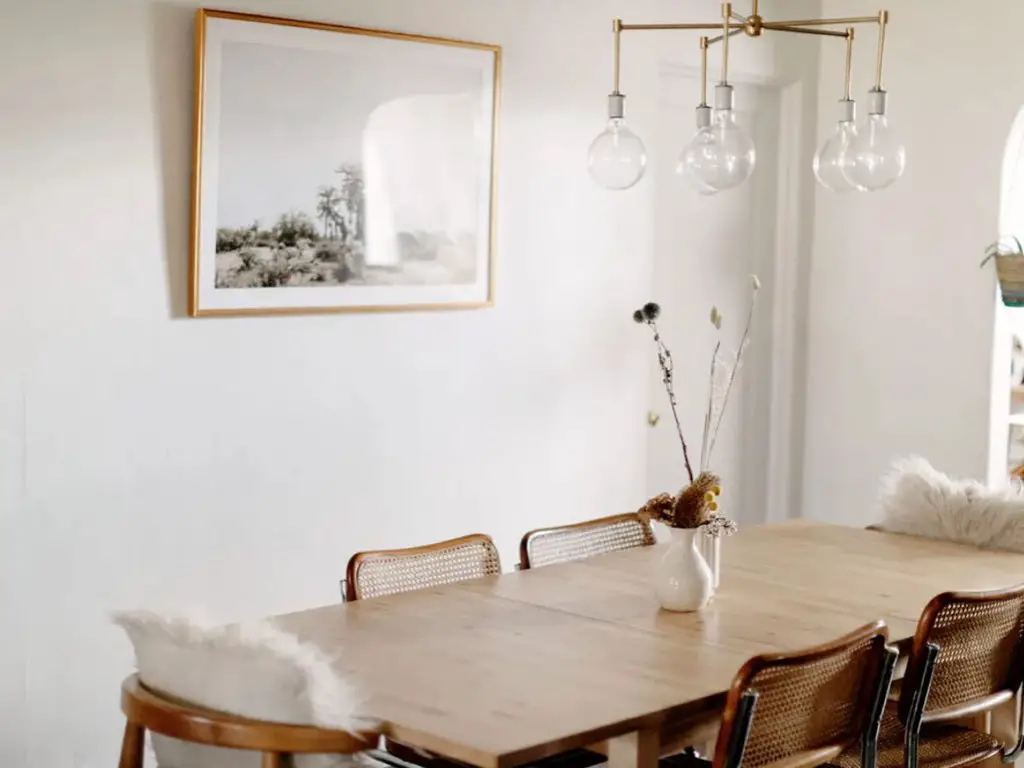 maison moderne familiale boheme retro salle à manger chic et élégante moderne table en bois fauteuil en cannage vintage tableau accroché au mur simple