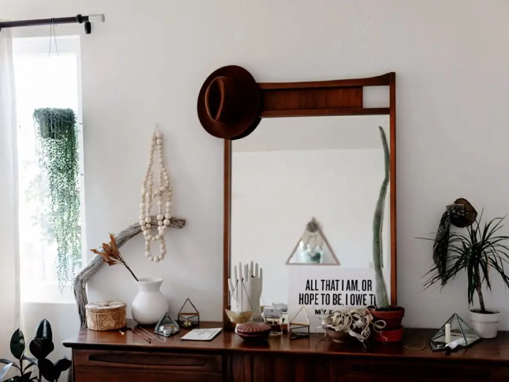 maison moderne familiale boheme retro chambre parentale chic et élégante maximalisme détails décoratifs posés sur la commode miroir encadrement bois sombre